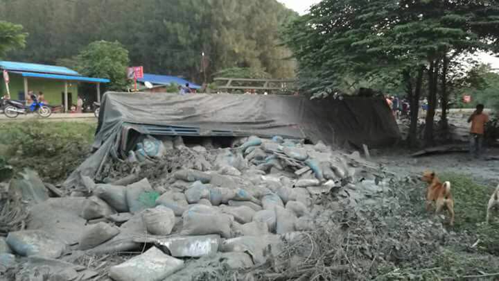 卡车侧翻，水泥包倒在地上。