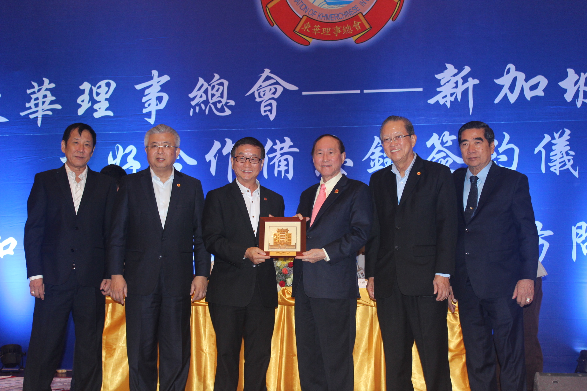 柬华理事总会会长方侨生（右三）赠送纪念品予新加坡中华总商会会长黄山忠（左三）。