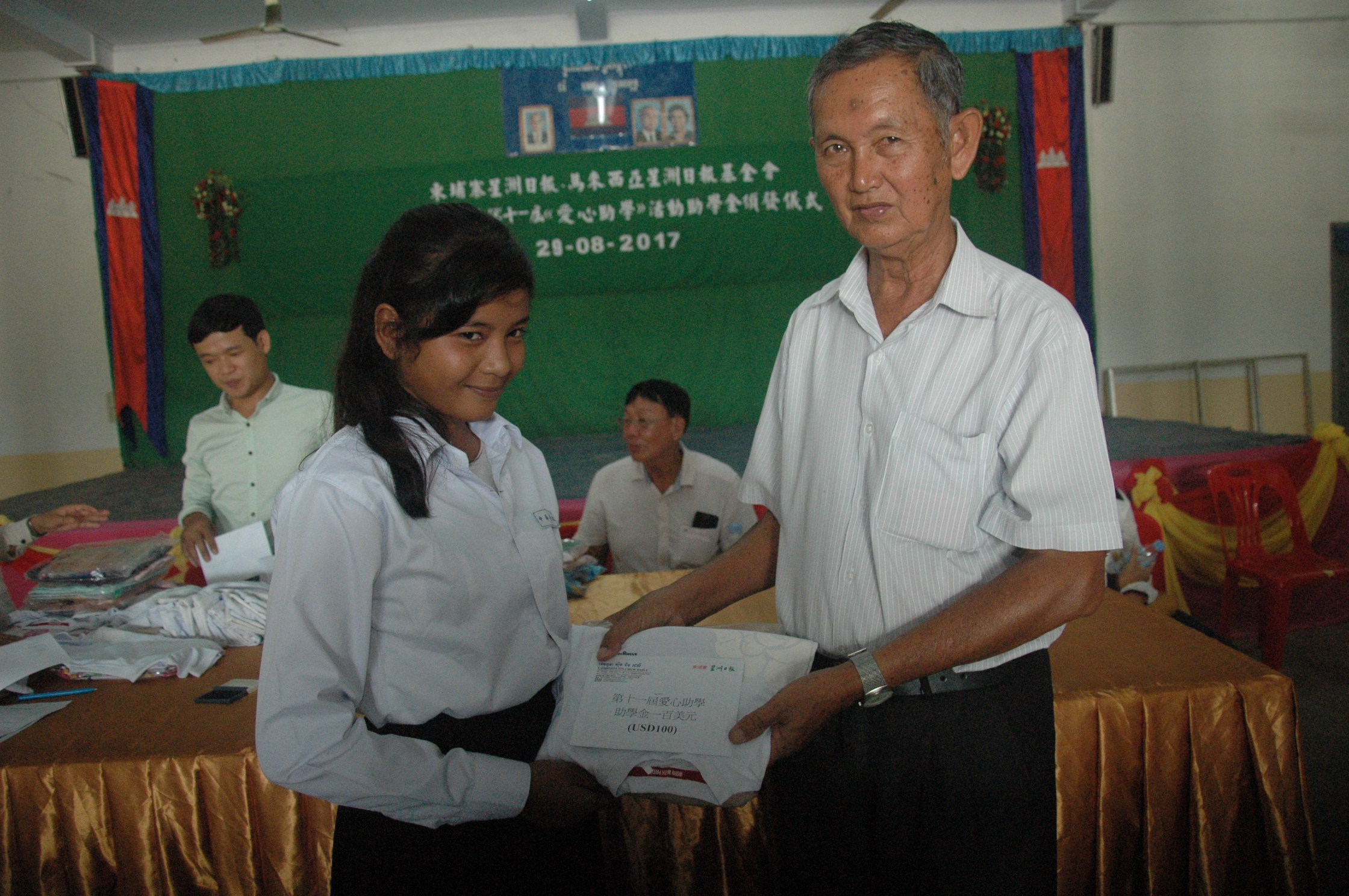 中华学校校长张如耀代表移交助学金和物资给受益学生。