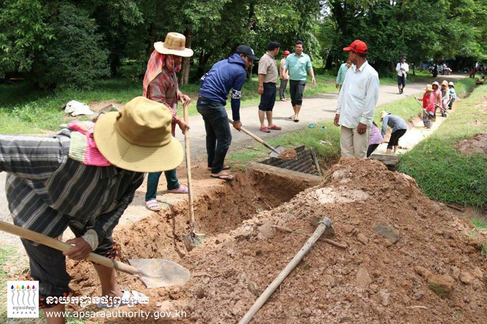 仙女女机构工作人员挖掘临时排水沟，以把积水排出吴哥窟。